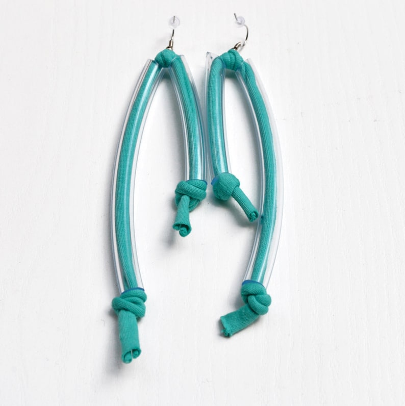 Peut inclure: Une paire de boucles d'oreilles bleu turquoise en tube de plastique transparent et en tissu. Le tissu est nou&eacute; en haut de chaque boucle d'oreille.
