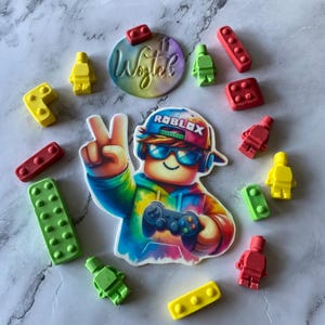 Può includere: Decorazione per torta a tema Roblox colorata con un personaggio con un controller, circondato da varie forme di mattoncini e mini-figure rosse, gialle e verdi. È presente anche il nome "Wojtek".