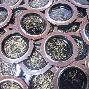 Pode incluir: Uma pilha de  apoios de copo octogonais marrons e pretos com um design metálico dourado. Os apoios de copo têm uma borda elevada e uma superfície lisa.