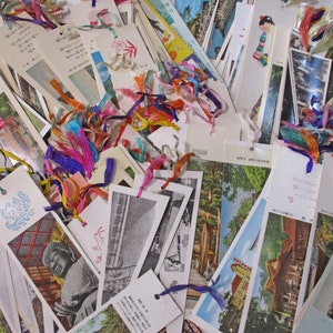 May include: A collection of vintage bookmarks featuring images of Japanese landscapes, buildings, and cultural icons. The bookmarks are made of paper and have colourful ribbons attached to them.