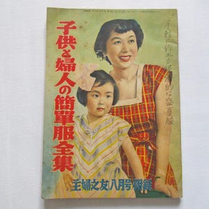 以下が含まれることがあります： 2人の女性が写っているヴィンテージ雑誌の表紙。一人は赤と白のチェック柄のドレス、もう一人はストライプのドレスを着ています。表紙のテキストは「子供と女性のシンプルな服の集まり」と「主婦の友 8月号」です。