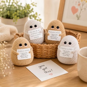 Puede incluir: Cuatro figuras de patata tejidas a ganchillo en tonos beige y blanco roto, cada una con ojos negros y un cartel blanco. Los carteles incluyen textos como 'Positive potato', 'Life was all out of lemons' y 'Poet was potato'. Una tarjeta dice 'you got this!'