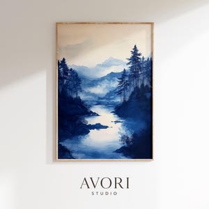 May include: A framed watercolor print of a serene landscape. The artwork depicts a river winding through a forest of tall, dark blue trees, with mountains in the background. The color palette is primarily shades of blue and white, with a touch of beige.