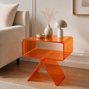 Peut inclure: Une table d'appoint en acrylique orange translucide avec un plateau en forme de C et une base croisée. La table présente une finition lisse et brillante ainsi qu'une section centrale creuse. Elle est faite d'une seule pièce moulée.