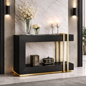Op de afbeelding: Een zwarte console met gouden accenten. De tafel heeft een rechthoekige vorm met een onderste plank. Hij is versierd met vazen met bloemen, kaarsen en een kleine decoratieve doos. De tafel staat tegen een marmeren muur.