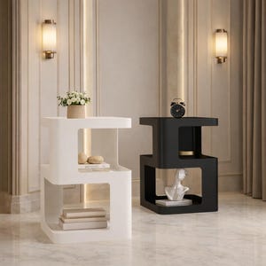 Peut inclure: Deux tables d'appoint modernes, une blanche et une noire, avec un design ouvert unique. La table blanche contient un petit arrangement floral et des objets décoratifs. La table noire présente une horloge et une sculpture de buste. Les tables sont dans une pièce bien éclairée.