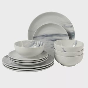 May include: A white marble-patterned dinnerware set. The set includes plates and bowls in various sizes. The plates and bowls have a gray and white swirl design. The dinnerware is stacked in groups, showcasing the full set.