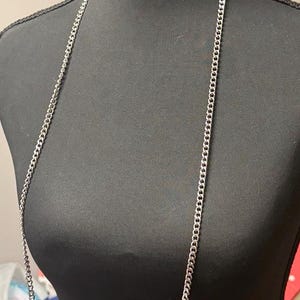May include: A silver-colored chain necklace displayed on a black mannequin. The necklace is a long, simple chain with a curb link design. A tag with the text "LaLa and Lace" is visible at the top.