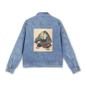以下が含まれることがあります： 背中に長方形のグラフィックが付いたライトブルーのデニムジャケット。グラフィックは、白い毛皮、赤と青の着物、そして恐ろしい表情をしたモンスターのカラフルなイラストを特徴としています。ジャケットは、ボタン留めとポケットを備えたクラシックなデザインです。