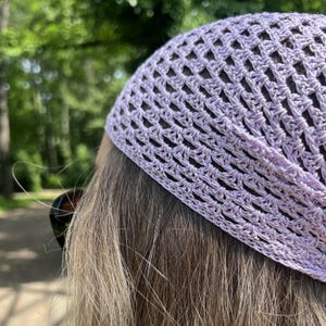 May include: A light lavender crochet head covering featuring an openwork diamond pattern. The accessory is crafted from fine yarn with a structured border along the edge, providing a textured appearance that sits securely over the top of the head.