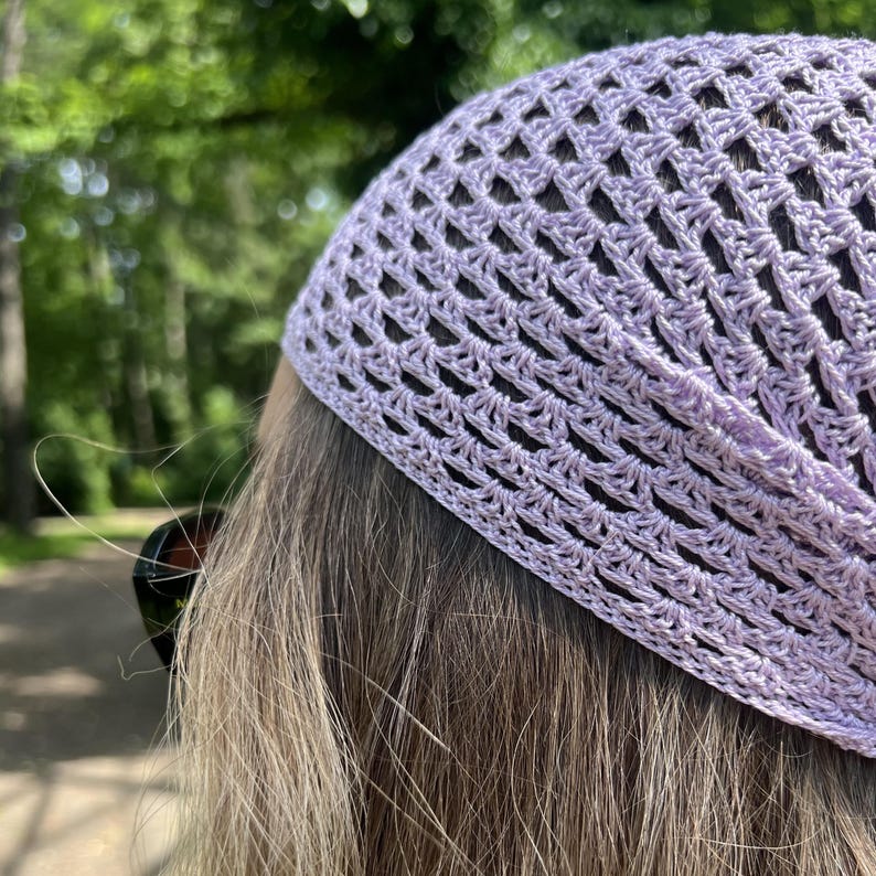 May include: A light lavender crochet head covering featuring an openwork diamond pattern. The accessory is crafted from fine yarn with a structured border along the edge, providing a textured appearance that sits securely over the top of the head.