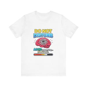 May include: White t-shirt featuring the text "DO NOT DISTURB" in yellow and blue above a red brain graphic. Below the brain is the text "ADHD processing... please wait." with a progress bar.