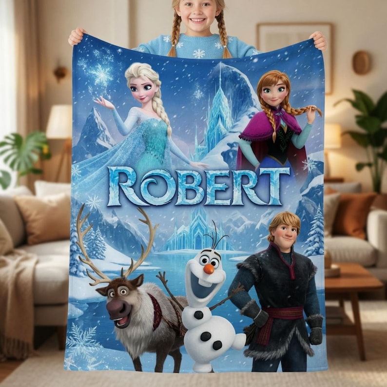 May include: A blue fleece blanket featuring the characters Elsa, Anna, Kristoff, Sven, and Olaf from Frozen, with the name ROBERT printed in large blue letters across the center against a snowy mountain landscape with snowflakes.