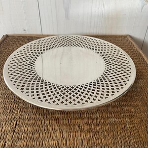 May include: A silver serving tray with a decorative, openwork design. The tray has a circular shape and a raised edge.