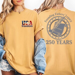 A woman wearing a yellow t-shirt with the text "USA freedom" and "Founding Fathers' Legacy" printed on it, along with a graphic of a feather and a document.