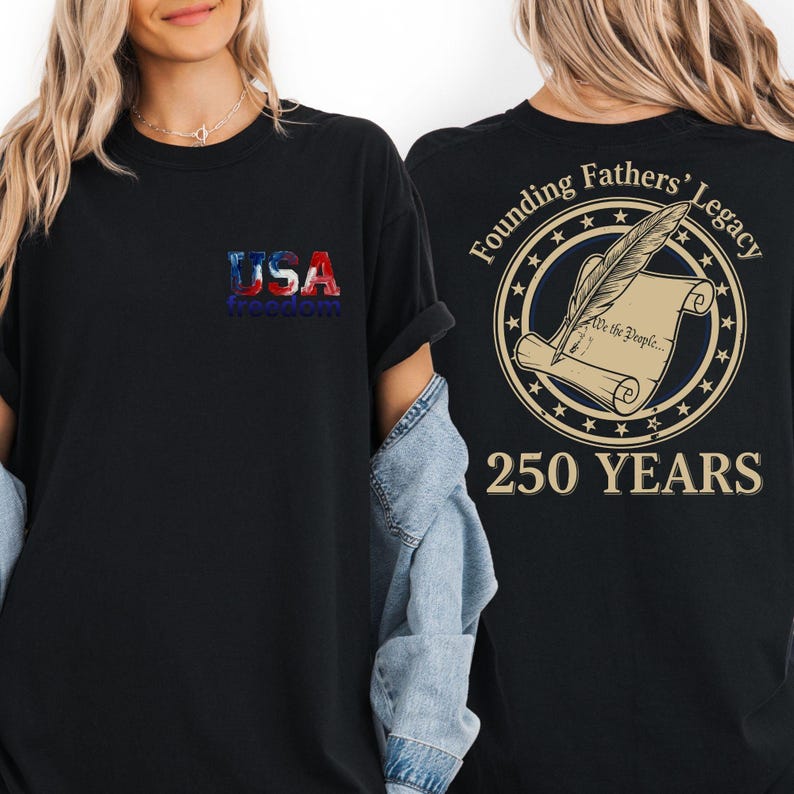 A woman wearing a black t-shirt with a graphic design on the back, which features a feather and a document, along with text that reads "USA freedom" and "Founding Fathers' Legacy 250 YEARS".