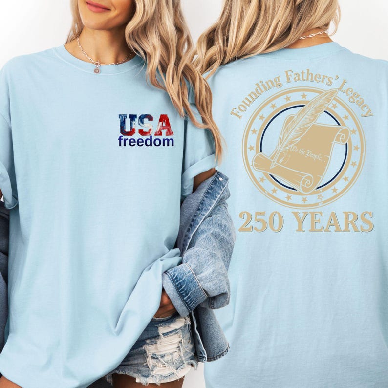 A woman wearing a light blue t-shirt with the text "USA freedom" and "Founding Fathers' Legacy" printed on it, along with a graphic of a feather quill and a document.