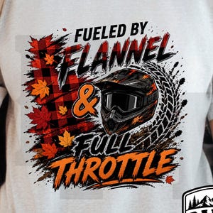 Könnte beinhalten: Ein hellgraues T-Shirt mit einem Grafikdruck mit dem Text FUELED BY FLANNEL & FULL THROTTLE. Das Design umfasst ein schwarz-rotes Karomuster, orangefarbene Ahornblätter, einen schwarzen Motocross-Helm und eine Reifenspur-Grafik.