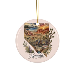 May include: A round, pale pink ceramic ornament hanging from a gold string. The center features a map of Nevada filled with a landscape illustration of mountains, horses, the Las Vegas skyline, the Hoover Dam, and the text Welcome to Fabulous Las Vegas.