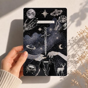 May include: A rectangular art print with a celestial theme. The print features a sword, stars, a moon, and a couple holding hands. The text "to the readers who look up at the stars and wish" is included. The print is held by a person.