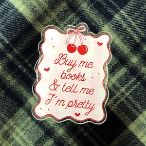 Puede incluir: Una taza de cerámica blanca con un asa negra y el texto "But First, Coffee" en negrita negra. La taza se encuentra sobre un fondo neutro, resaltando su diseño sencillo.