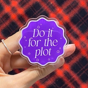 Puede incluir: Una pegatina transparente con borde festoneado con el texto "Do it for the plot" en blanco sobre un fondo morado. Pequeñas estrellas blancas rodean el texto. La pegatina se sostiene en una mano sobre un fondo de cuadros rojos y negros.