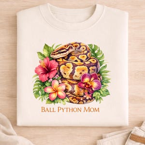 May include: A set of three ceramic mugs with a speckled, cream-colored glaze. Each mug features a different hand-painted floral design in shades of blue, green, and yellow. The mugs have a simple, rounded shape and a comfortable handle.