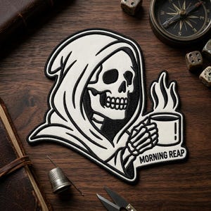 May include: A black and white patch featuring a Grim Reaper skull in a hooded robe, holding a steaming coffee cup. The text "MORNING REAP" is below the cup. The patch is on a wooden surface.