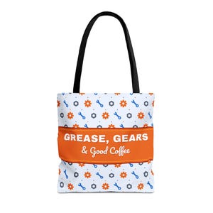 May include: A white tote bag with black handles featuring a repeating pattern of orange gears, blue wrenches, and gray hexagonal nuts. A horizontal orange band across the center displays the white text: GREASE, GEARS & Good Coffee.