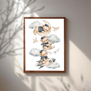 May include: A framed wall art print featuring three watercolour illustrations of teddy bears in navy blue sailor outfits. One bear rests on a crescent moon, another holds a ship anchor, and the third rides a rocket ship, all surrounded by clouds.