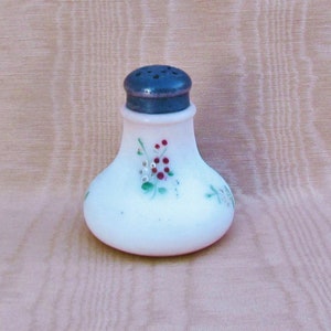May include: A white milk glass salt shaker with a silver top and hand-painted floral design featuring red and green accents.