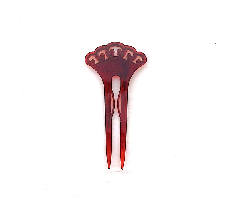 Puede incluir: Un peine para el cabello de color rojo oscuro con una parte superior decorativa en forma de abanico y dos p&uacute;as largas y puntiagudas. El peine tiene un dise&ntilde;o calado en la parte superior y est&aacute; hecho de un material transl&uacute;cido. Es un accesorio para el cabello.