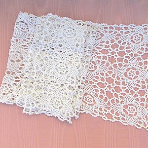 May include: A stack of white, open-weave crochet doilies. The doilies have a delicate, lacy pattern with floral and geometric shapes. The crochet work is intricate and detailed, with a scalloped edge. The doilies are arranged on a pink surface.