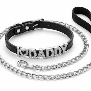May include: A black leather dog collar with the text "I LOVE DADDY" spelled out in silver rhinestone letters. A matching silver chain leash and black handle complete the set.