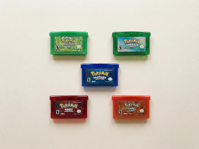 May include: Five colorful Pokemon Game Boy Advance cartridges. The cartridges are green, blue, and red, with the game titles visible. The games include FireRed, LeafGreen, Ruby, Sapphire, and Emerald versions.