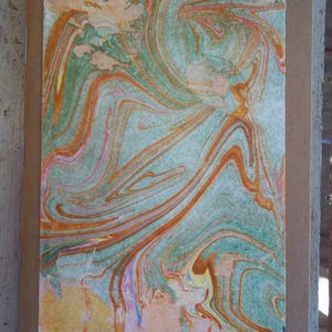 May include: A handmade marbled paper notebook cover with a swirling pattern of orange, green, pink, and yellow.