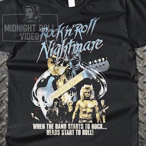 May include: A black t-shirt featuring a graphic print with the text Rock'n'Roll Nightmare and When the band starts to rock... heads start to roll! The design includes a stylized electric guitar, a skull, and a band of musicians in the foreground.