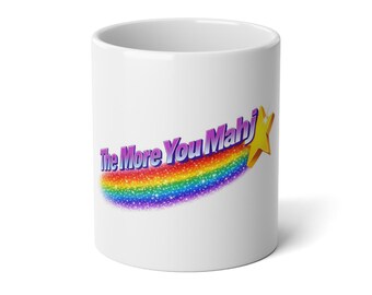 May include: White ceramic mug with the text "The More You Mahj" in a rainbow design with a gold star. The mug is cylindrical and has a glossy finish. The design features a rainbow arc with glitter.