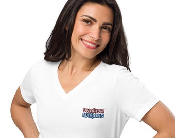 May include: A white V-neck t-shirt with the word "MAHJONG" embroidered in red and blue. The text is in a stylized font. The shirt is made of a soft material and is being worn by a person.