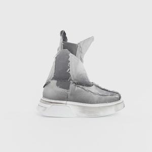 May include: A gray ankle boot with a unique, deconstructed design. The boot features a layered, distressed appearance with visible stitching and a thick, white sole. The overall aesthetic is modern and edgy.