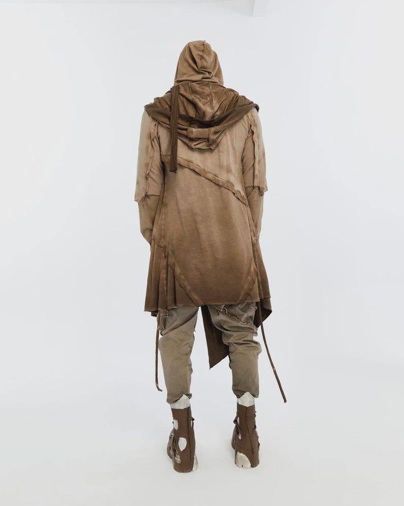 May include: A brown hooded coat with a layered design, paired with matching pants and boots. The coat features a draped front and asymmetrical hem. The outfit is in shades of brown, creating a cohesive, earthy aesthetic.