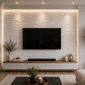 May include: A wall-mounted television centered on a white textured stone wall flanked by two white fluted columns. Below the television is a long, low-profile media console with a wood top and white cabinets, accented by decorative vases and greenery.