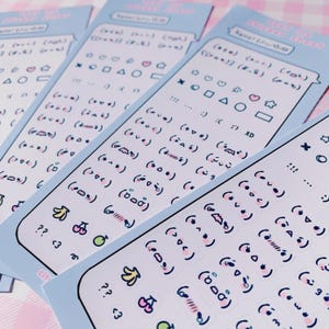 May include: Four light blue sticker sheets with various emoji and fruit designs. The stickers include faces, shapes, and fruits like bananas and cherries. The text "hello! sticker sheet" is at the top of each sheet.