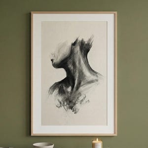 Op de afbeelding: Een ingelijste houtskooltekening van een menselijke nek en een gedeeltelijk gezicht. Het kunstwerk is in grijstinten en zwart, met de nadruk op de nek en schouders. De tekening staat tegen een lichtbeige achtergrond, ingelijst in een licht houten frame.