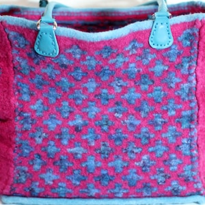 Könnte beinhalten: Eine rosa und blaue Tragetasche mit geometrischem Muster. Die Tasche hat zwei blaue Henkel und eine Reißverschlusstasche auf der Vorderseite.