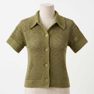 May include: Olive green short-sleeved knit shirt with a collared neckline and button-down front. The shirt has a textured, open weave design and is displayed on a mannequin. The buttons and collar match the shirt's color.
