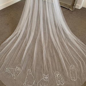 Peut inclure: Un long voile de mariage blanc et transparent avec un motif brodé délicat de différentes races de chiens le long du bord inférieur. Le voile est drapé, mettant en valeur les détails complexes et le tissu fluide. Le fond est neutre.