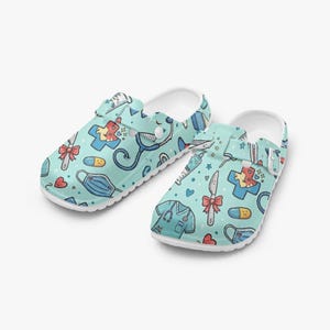 May include: Light blue clogs with a white sole, patterned with medical symbols like stethoscopes, scrubs, pills, and surgical tools. These comfortable clogs are designed for support and are ideal for healthcare professionals.