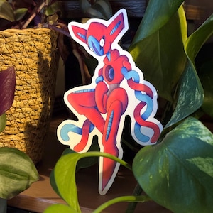 May include: A sticker depicting a red and blue cartoon character with a distinctive design. The character has a red body with blue details and flowing blue tendrils. The sticker is positioned amongst green plants.