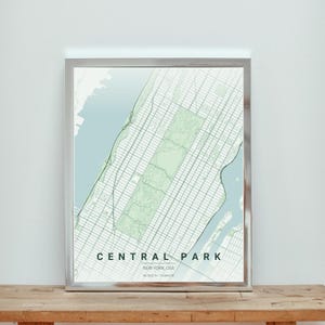 May include: A framed map print of Central Park, New York City. The map shows the park in light green, surrounded by a grid of streets and waterways in blue and white. The words "CENTRAL PARK" are printed at the bottom, with the city's coordinates.
